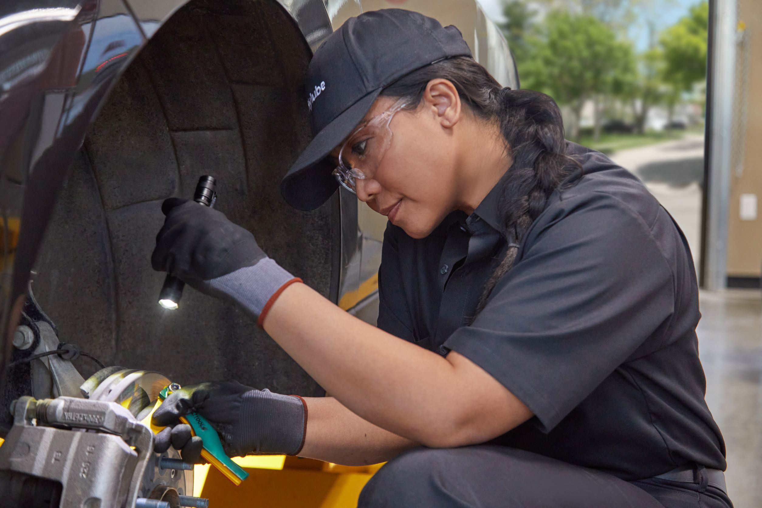 jiffy lube employee checking the disc brakes of a car